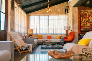 Ein gemütliches Wohnzimmer mit einer Couch, Sesseln, einem Couchtisch und einem Hängestuhl.