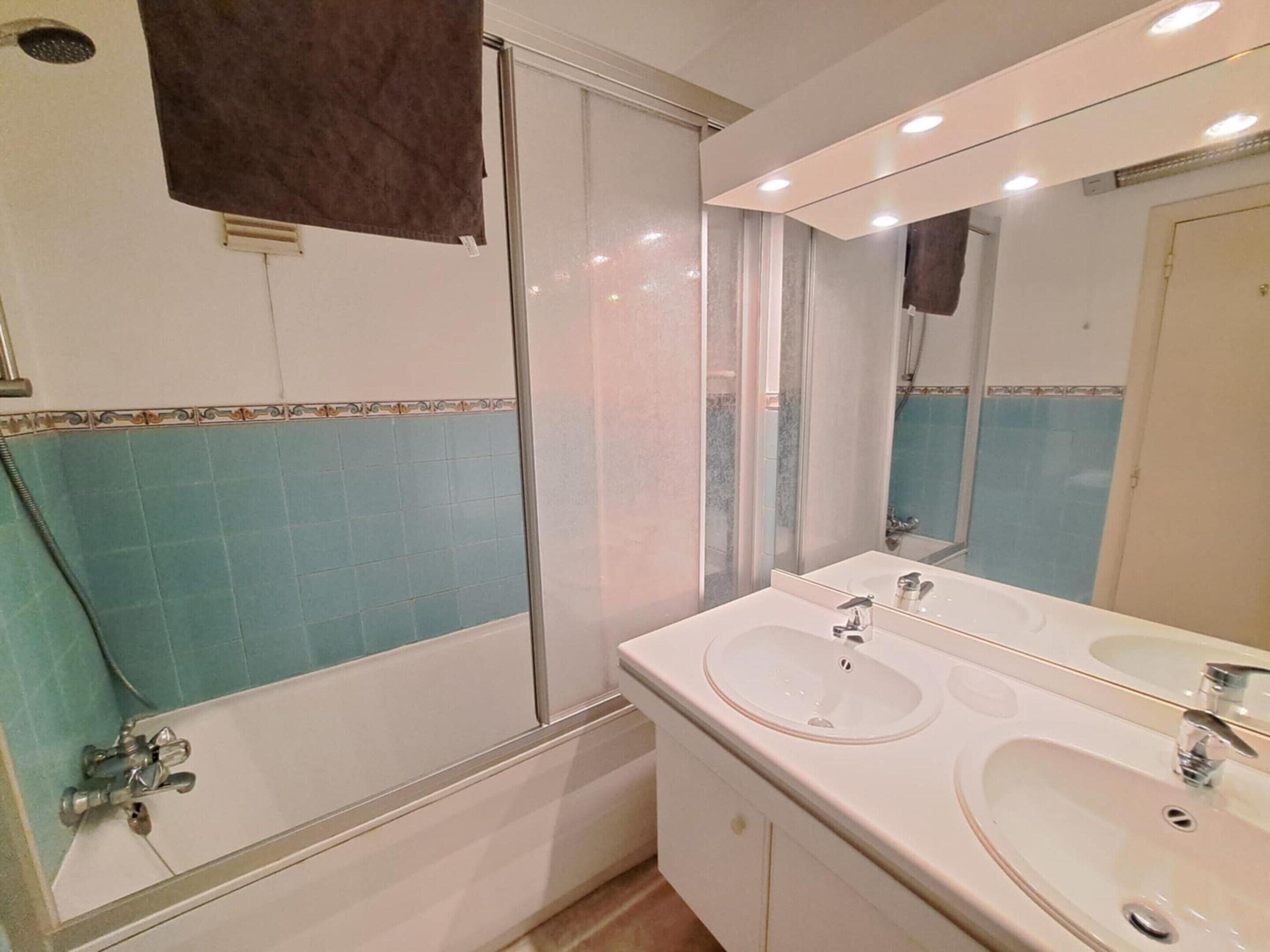 Ein Badezimmer mit Dusche, zwei Waschbecken, einem Spiegel und einem Handtuchhalter.