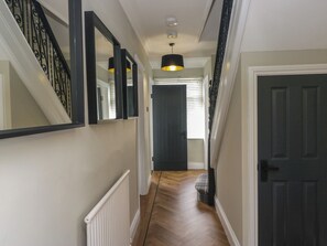 A hallway with a staircase, a radiator, a door, and a window with blinds. - 5 Thornbarrow Road (Windermere)