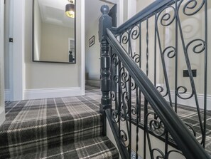A staircase with a black metal railing and a plaid carpet. - 5 Thornbarrow Road (Windermere)