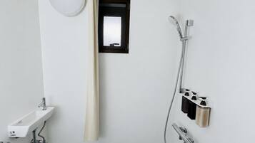 Ein Badezimmer mit Waschbecken, Dusche und kleinem Fenster.
