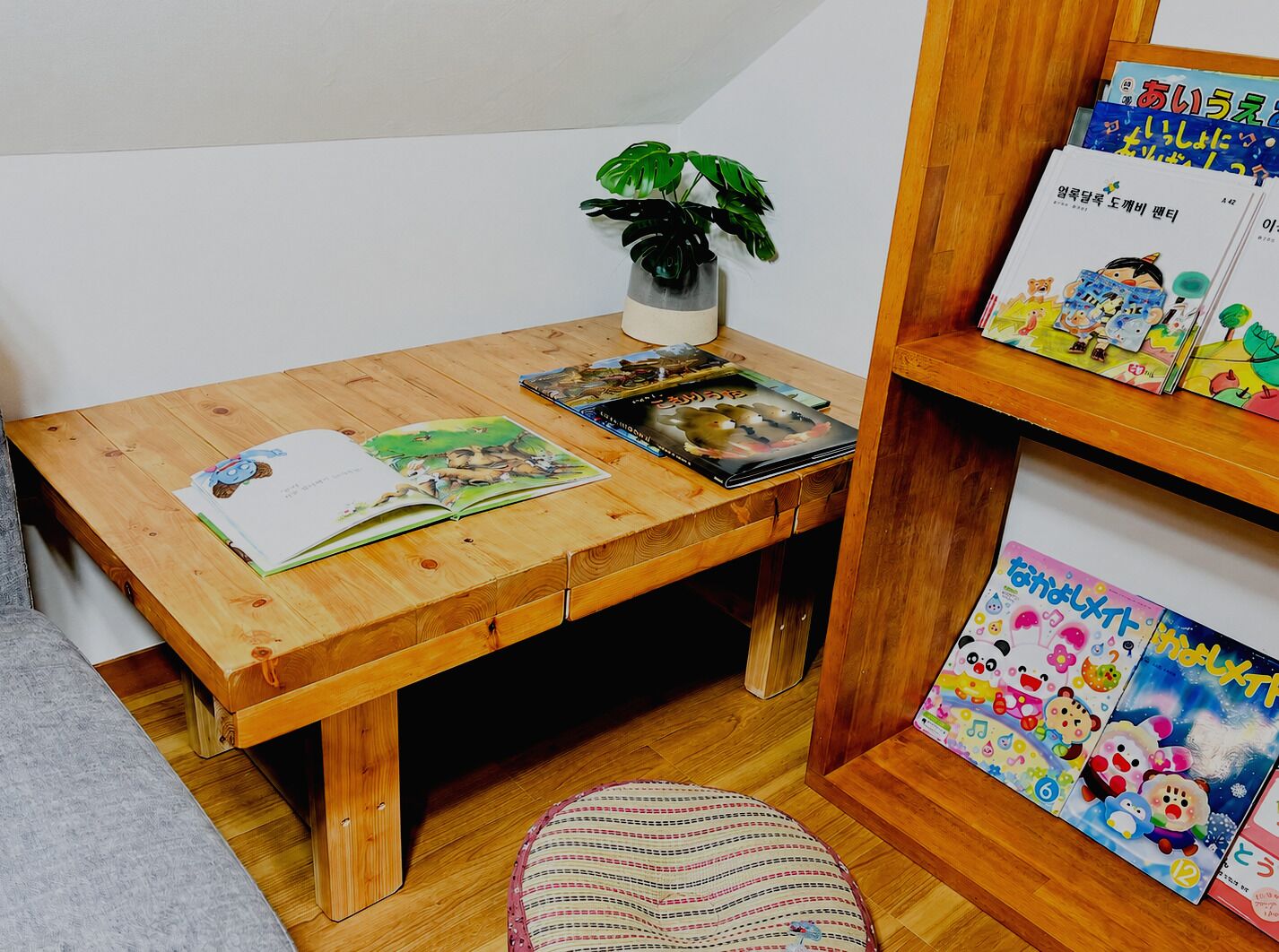A wooden desk with books, a plant, and a small shelf with colorful items.
