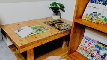 A wooden desk with books, a plant, and a small shelf with colorful items.