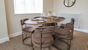 A dining area with a round table, four chairs, and a mirror on the wall. - Bella Vista (Llandudno)