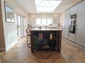 A modern kitchen with a central island, a skylight, and a view to the outside. - Bella Vista (Llandudno)