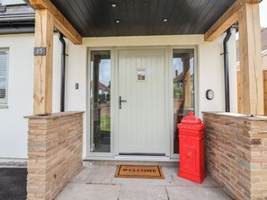 A front door with a glass panel, a red mailbox, and a welcome mat. - Bella Vista (Llandudno)