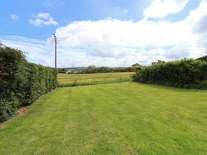 A grassy field with a hedge on one side and a utility pole in the distance. - Bella Vista (Llandudno)