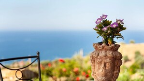 Un jarrón con un arreglo floral sobre una mesa con vista al mar.