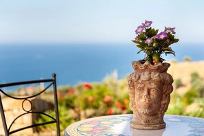 Eine Vase mit Blumen auf einem Tisch, der Meerblick bietet.