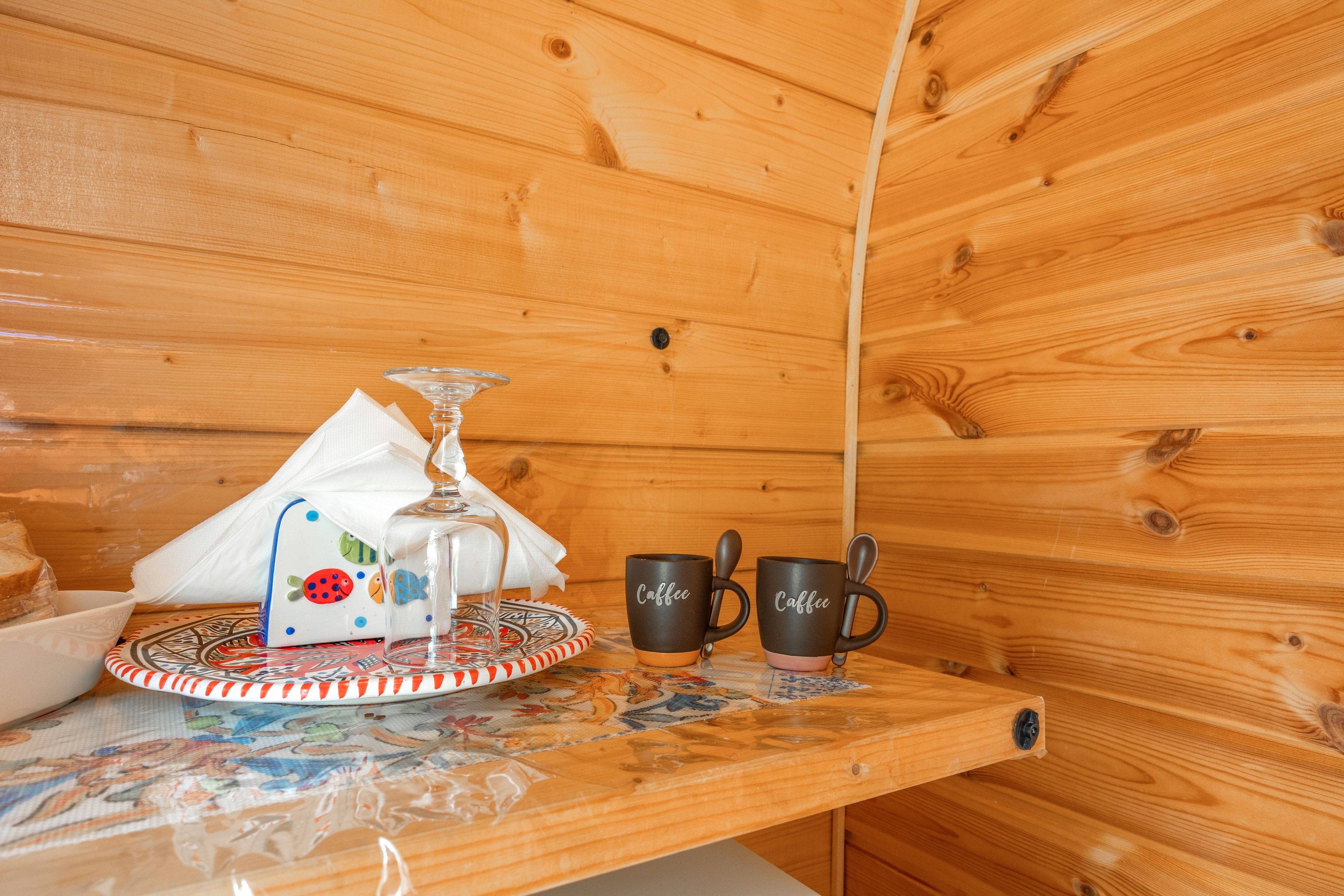 Un intérieur en bois avec une table sur laquelle sont disposés un verre, deux tasses et une assiette avec une serviette.