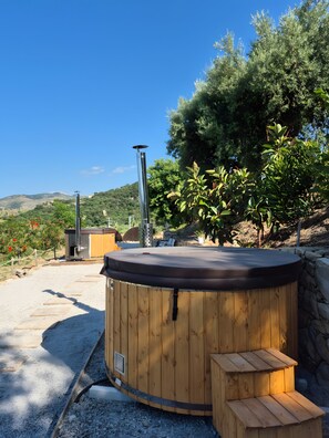 Ein Whirlpool mit Holzverkleidung, einer Steinwand und Blick auf eine Berglandschaft.