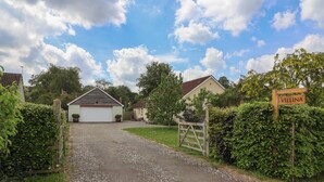 A gravel driveway leading to a house with a garage, surrounded by greenery and a clear sky. - Villina (Somerton)