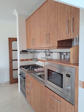 Eine moderne Küche mit Holzausstattung, Edelstahlgeräten und einer gefliesten Spritzschutzwand.