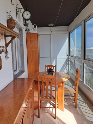 Ein sonnendurchflutetes Zimmer mit einem Holzespeisesaal und Stühlen, einer Uhr und Blick durch große Fenster.