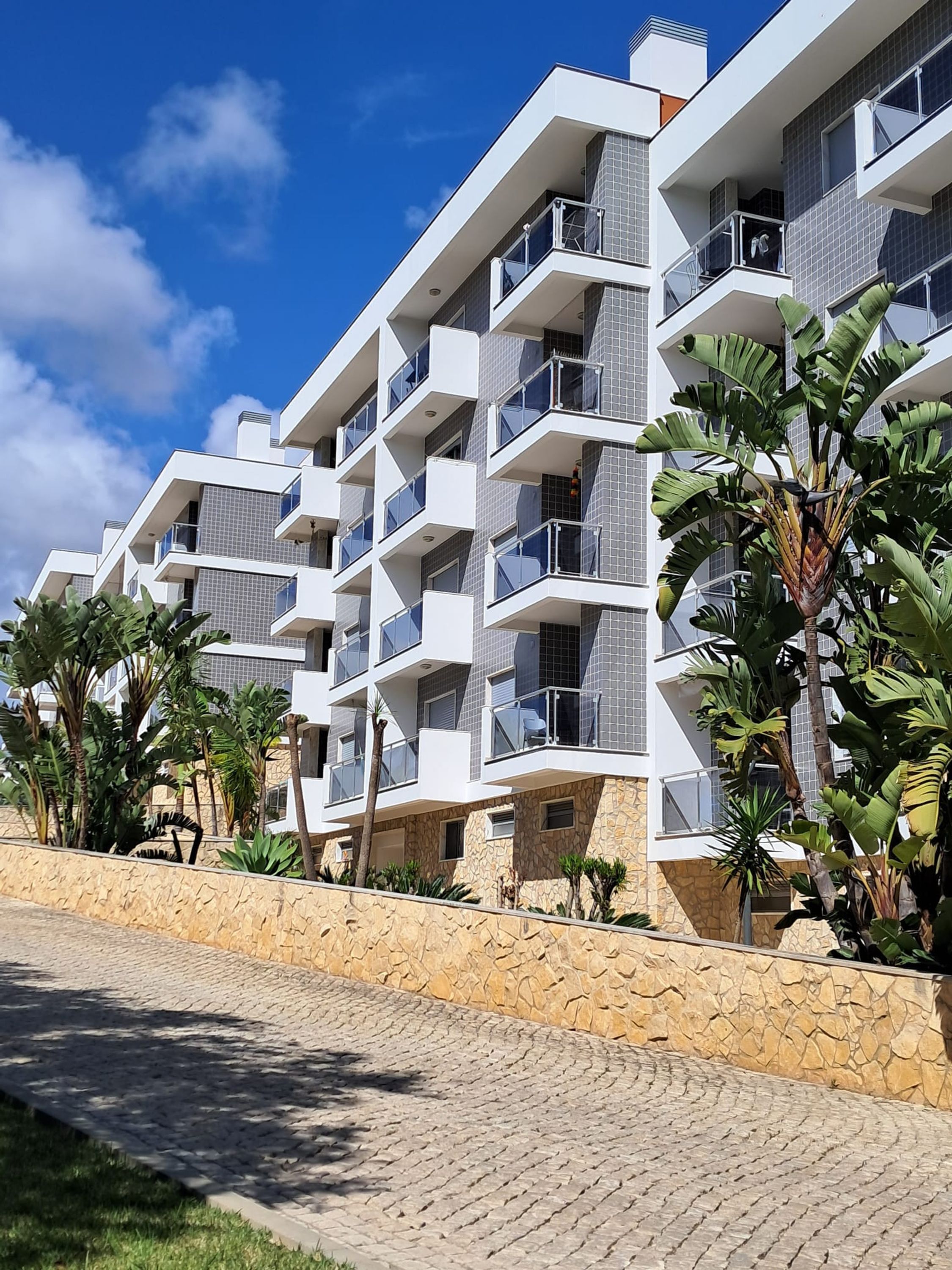 A multi-story hotel with balconies, a stone facade, and tropical plants.