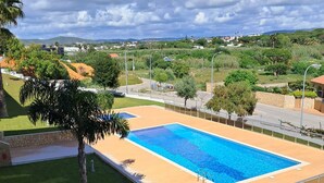 Una piscina rectangular con superficie de agua azul cristalina, rodeada por una terraza de arena y delimitada por un muro de piedra bajo.