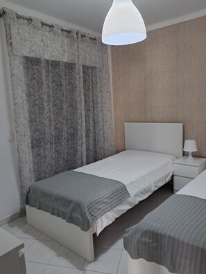 A bedroom with a bed, bedside table, lamp, and curtains. - T2 Vista MAR in Quarteira (Faro)