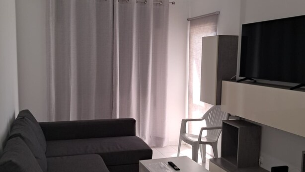 Een moderne woonkamer met een modulaire bank, een televisie, een klein tafeltje en een stoel.