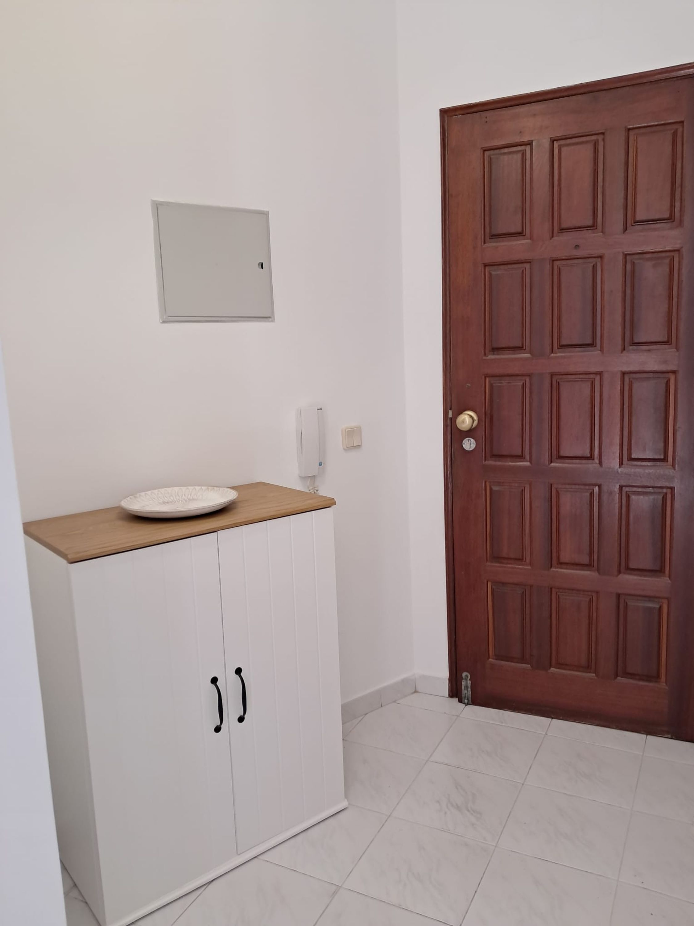 A room with a white cabinet, a wooden door, and a tiled floor.
