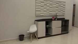Quarto moderno com ar condicionado embutido, mesa de console contemporânea, cadeira branca e um painel decorativo na parede.