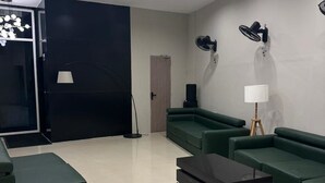 Uma sala de estar moderna com um sofá de canto, uma mesa de centro, iluminação embutida no teto, um abajur e uma porta.