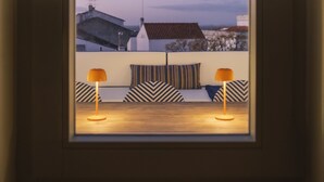 Una habitación con vista a edificios, una ventana y dos lámparas.