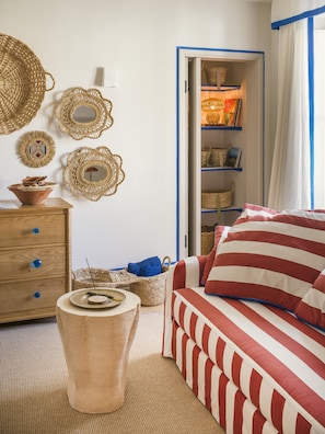 Une pièce comprenant un lit, une commode, un panier et une étagère avec des paniers.