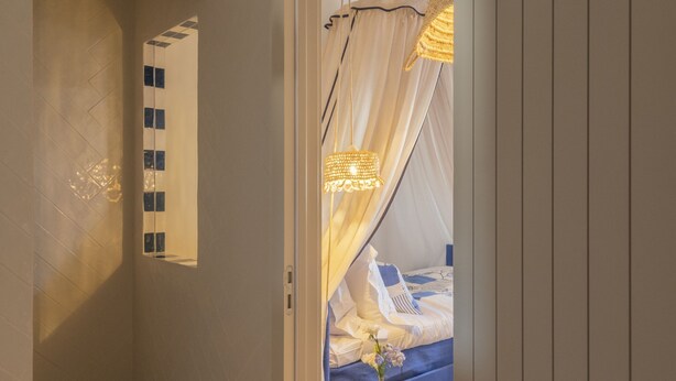 Un dormitorio con cama, mesita de noche y lámpara colgante.