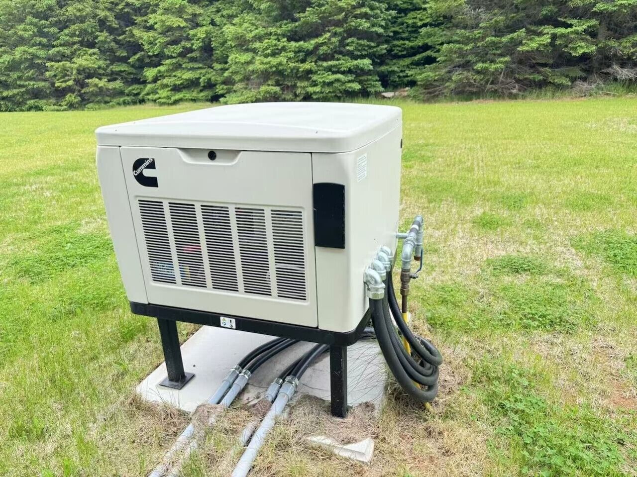 En portabel luftkonditioneringsenhet med en logotyp, ett ventilationsgaller och slangar, placerad på en betongplatta utomhus.