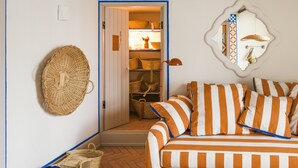 A cozy room with a striped sofa, wicker baskets, and a small reading area. - Al Porta Townhouse by Cadenzalux (Beja)