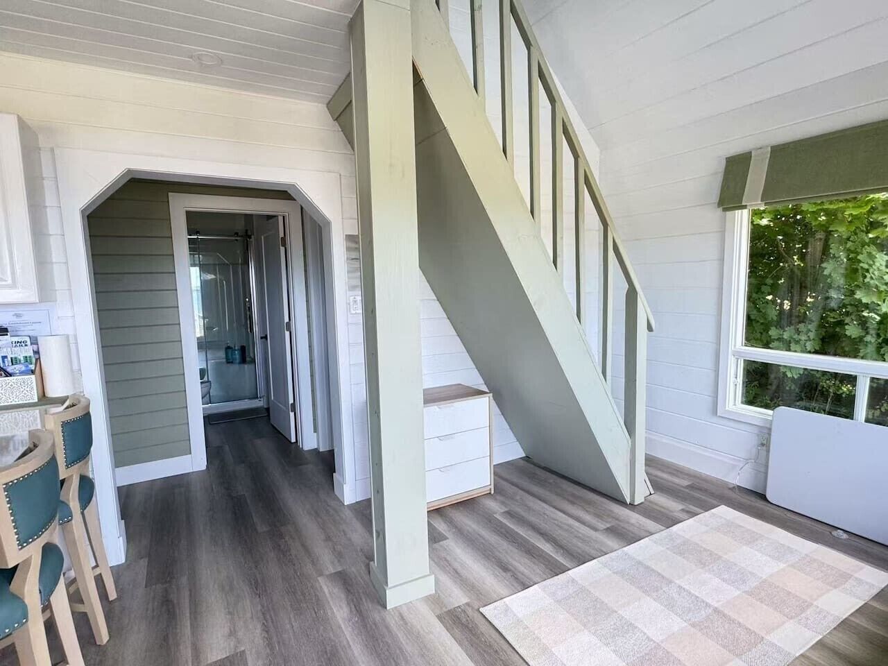 Ett rymligt interiört utrymme med en trappa, en matplats och utsikt över grönområden utanför.