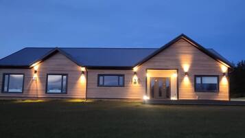 A two-story house with a sloped roof, multiple windows, and exterior lighting.