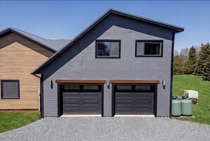 A modern two-story house with a garage, a wooden deck, and a well-maintained lawn.
