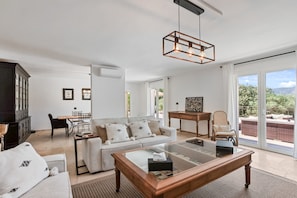 A modern living room with a glass coffee table, a sofa, and a dining area.