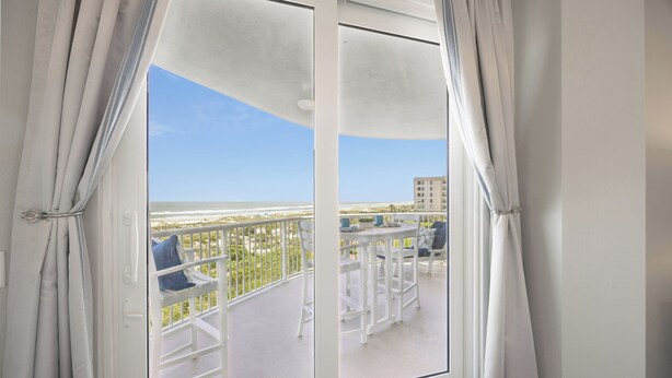 Un balcon avec des meubles blancs et une vue sur l’océan.