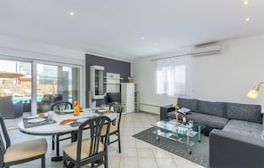 Ein modernes Wohnzimmer mit Essbereich, einer Couch und einem Glastisch.