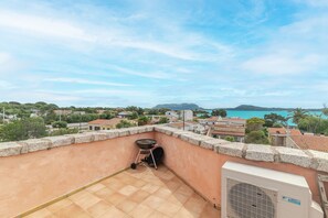 Eine Dachterrasse mit Meerblick, einem Grill und einer Klimaanlage.