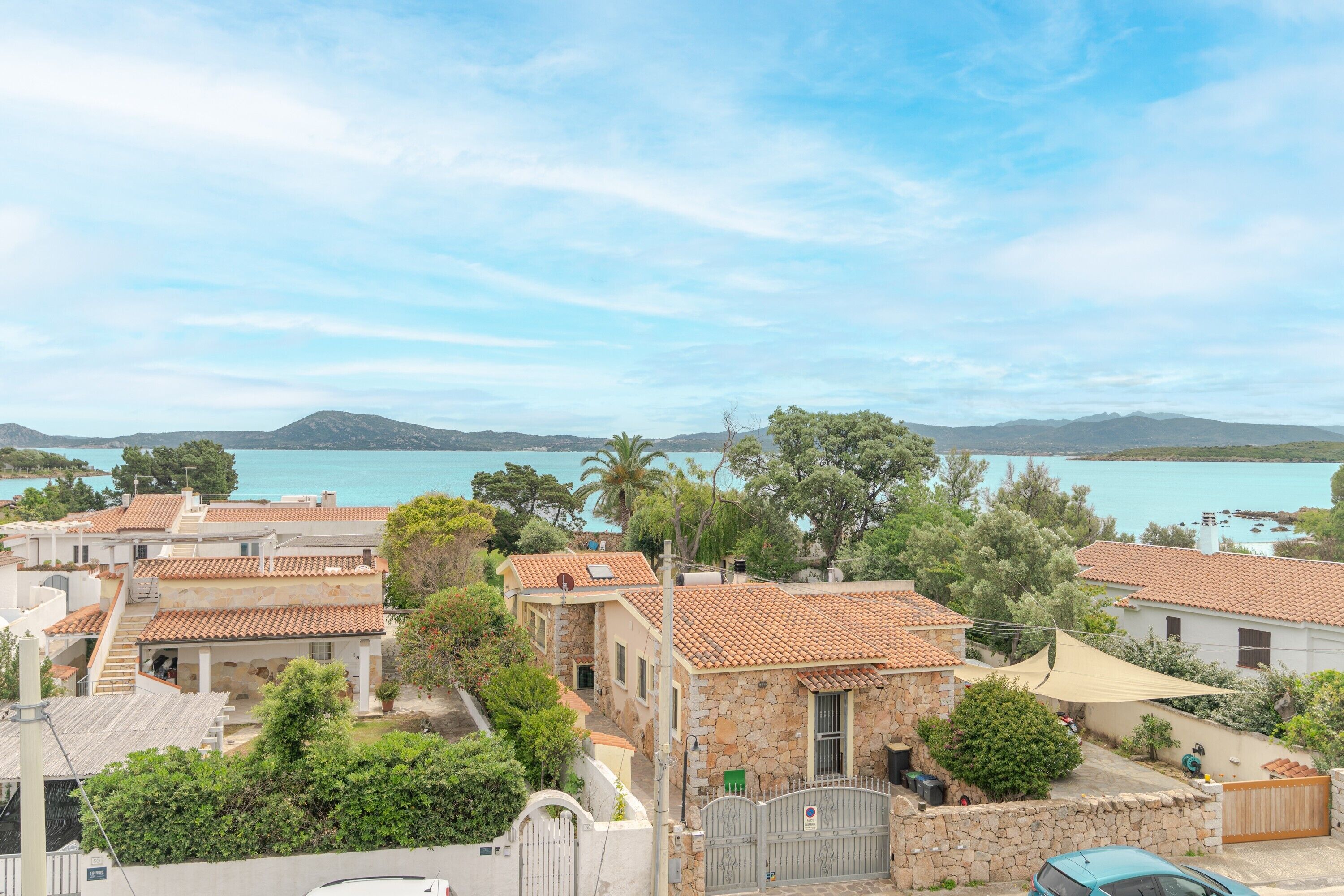 A coastal residential area with stone buildings, a clear sky, and a view of the sea.