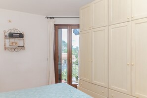 Ein Schlafzimmer mit Bett, Kleiderschrank und einem Fenster mit Blick auf Gebäude.