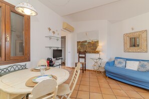 Ein Essbereich mit Tisch, Stühlen, einem Fernseher und einem blauen Sofa.