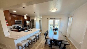 Una cocina moderna con una isla central, taburetes de bar y una mesa de comedor con sillas.