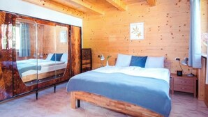 A wooden-paneled room with a large bed, a mirror, and a nightstand.