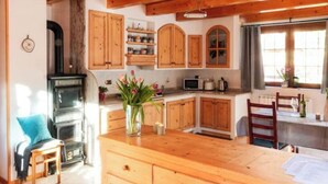 A kitchen with wooden cabinets, a stove, a microwave, and a dining area with a table and chairs.