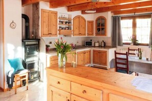 A kitchen with wooden cabinets, a stove, a microwave, and a dining area with a table and chairs.