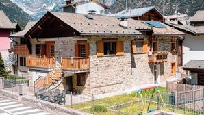A stone building with wooden balconies and a ski lift in the background.