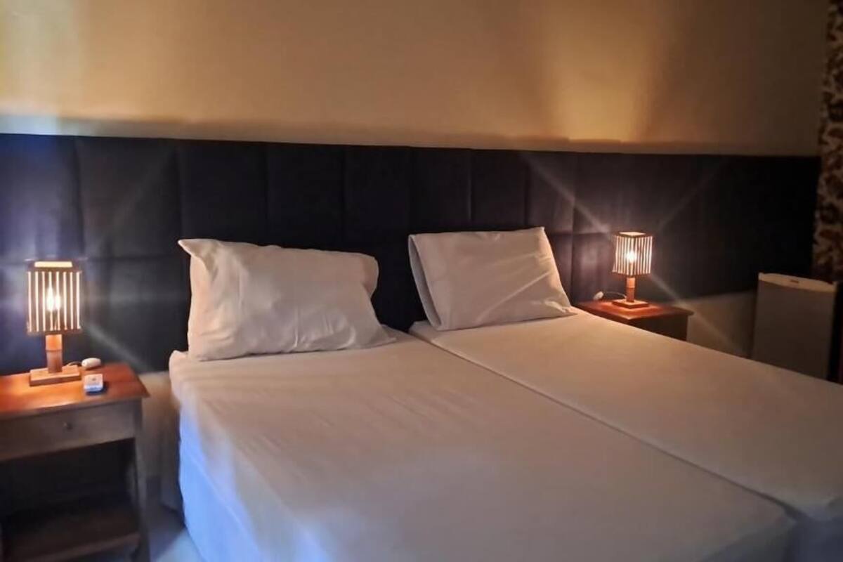 Una habitación de hotel con una cama, dos mesitas de noche con lámparas, un cabecero y una pared con diseño.