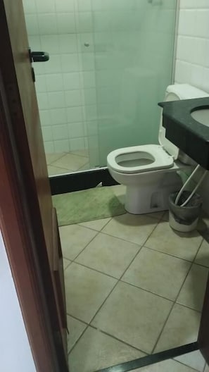 Casa de banho com sanita, lavatório e um contentor de lixo.
