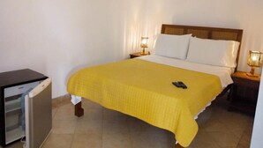 A single bed with a yellow bedspread, a bedside lamp, and a small refrigerator. - Pousada e Restaurante do Recreio (Rio de Janeiro)