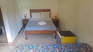 A bedroom with a bed, bedside lamps, a bedside table, a small bedside table, and a colorful patterned rug. - Pousada e Restaurante do Recreio (Rio de Janeiro)