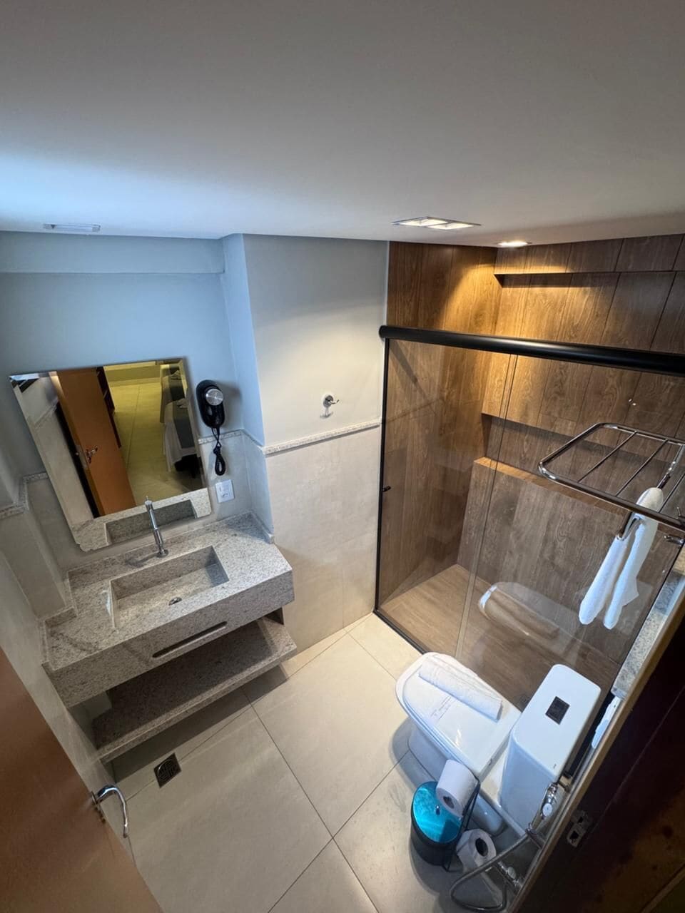 Un baño moderno con ducha de vidrio, lavabo con espejo y retrete.
